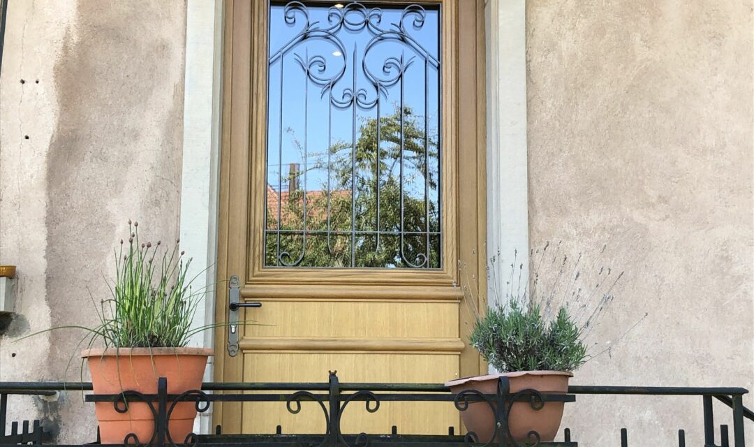 Une porte d'entrée sur mesure en bois avec un vitrail et une poignée en laiton.